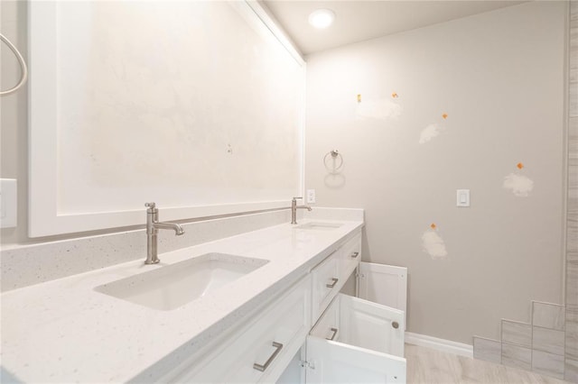 full bathroom featuring baseboards, a sink, and double vanity