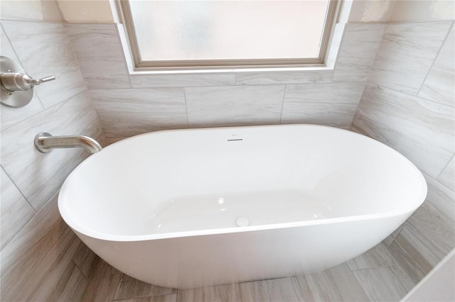 full bathroom featuring a freestanding bath and tile walls