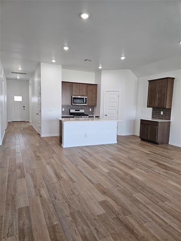 kitchen with tasteful backsplash, white range, light hardwood / wood-style floors, and a kitchen island with sink