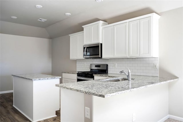 kitchen featuring white cabinetry, sink, backsplash, kitchen peninsula, and appliances with stainless steel finishes