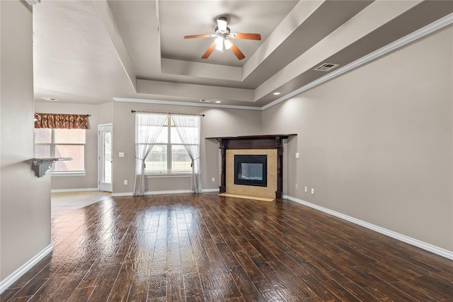 unfurnished living room with a fireplace, a raised ceiling, ceiling fan, and dark wood-type flooring