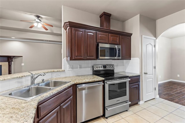 kitchen featuring ceiling fan, sink, light hardwood / wood-style floors, decorative backsplash, and appliances with stainless steel finishes