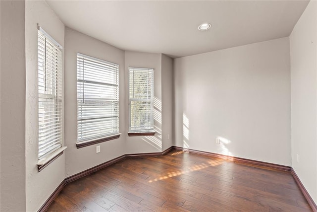 unfurnished room featuring a healthy amount of sunlight and dark wood-type flooring