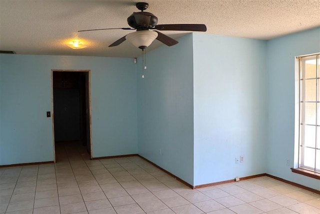 empty room featuring ceiling fan, light tile patterned flooring, and a textured ceiling