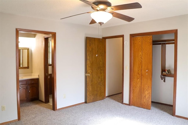 unfurnished bedroom with connected bathroom, light colored carpet, and ceiling fan