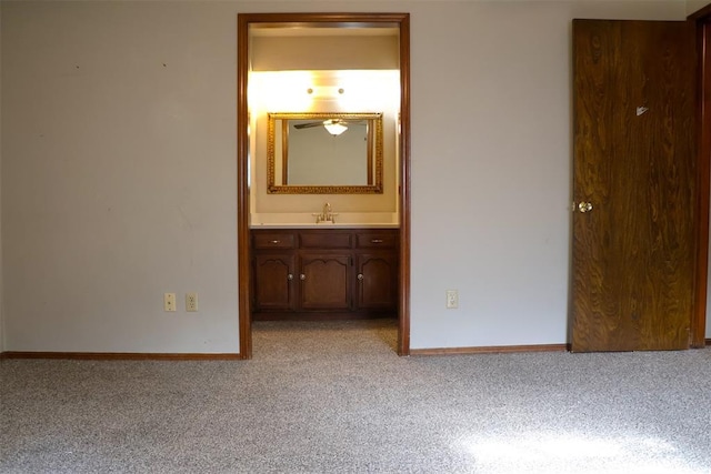 unfurnished bedroom featuring ensuite bathroom, light colored carpet, and sink