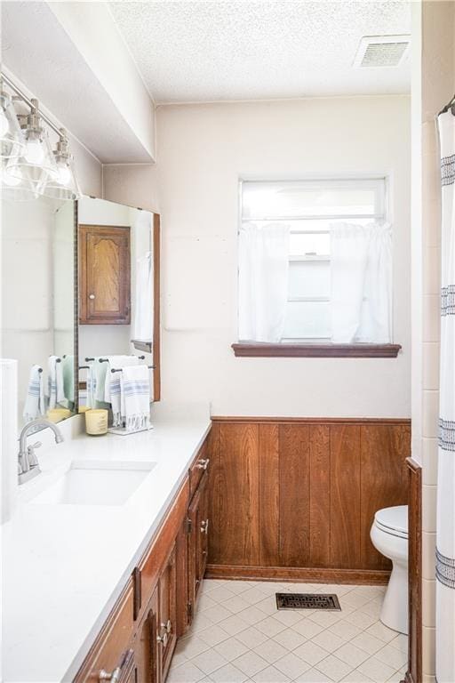 bathroom featuring tile patterned floors, vanity, a textured ceiling, and toilet