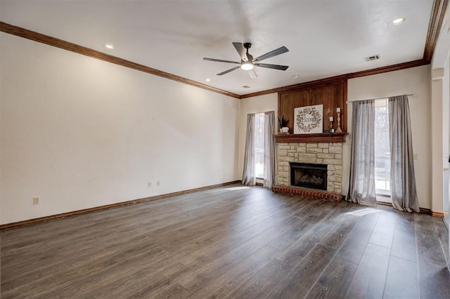 unfurnished living room with ceiling fan, dark hardwood / wood-style floors, ornamental molding, and a stone fireplace