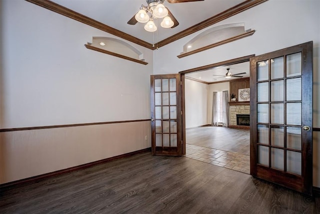 empty room with ceiling fan, dark hardwood / wood-style floors, crown molding, and french doors