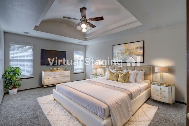 bedroom with a raised ceiling, ceiling fan, and light carpet