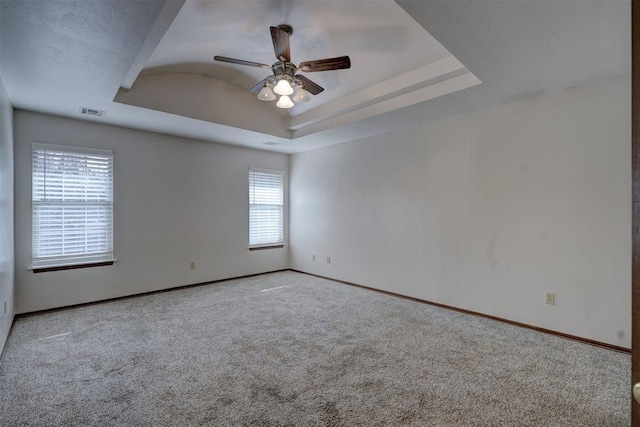 carpeted spare room with ceiling fan and a tray ceiling