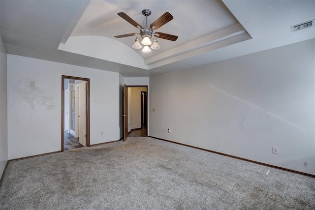 unfurnished bedroom featuring ceiling fan, lofted ceiling, light colored carpet, and a raised ceiling