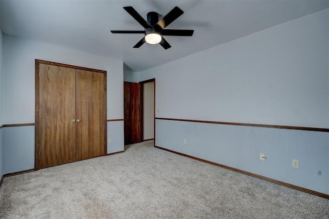 unfurnished bedroom featuring light carpet, ceiling fan, and a closet