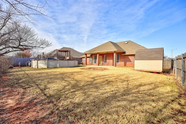 back of house featuring a fenced in pool, a lawn, and a storage shed