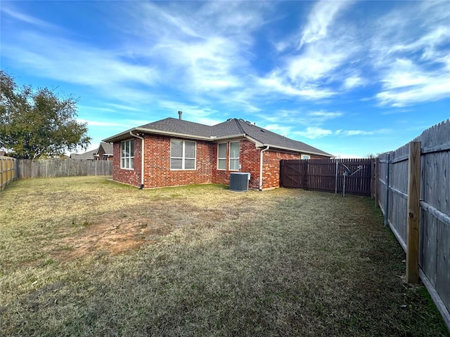 rear view of property with a yard and central AC