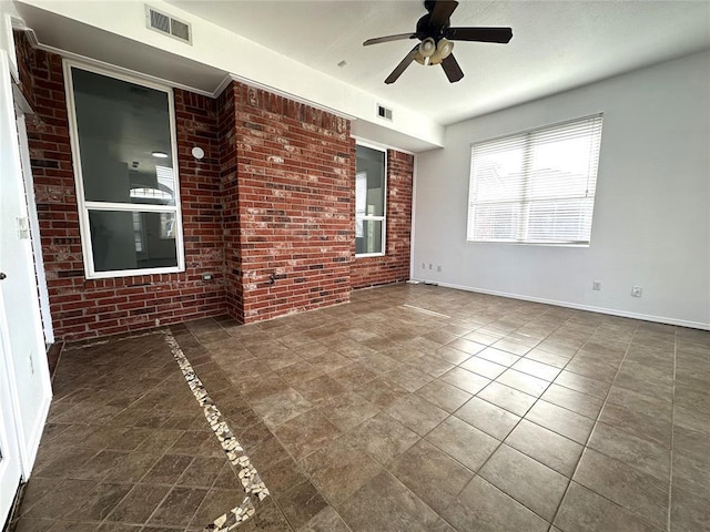 unfurnished room with ceiling fan and brick wall