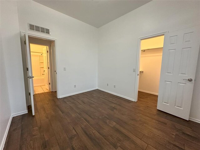 unfurnished bedroom featuring a walk in closet and dark hardwood / wood-style flooring