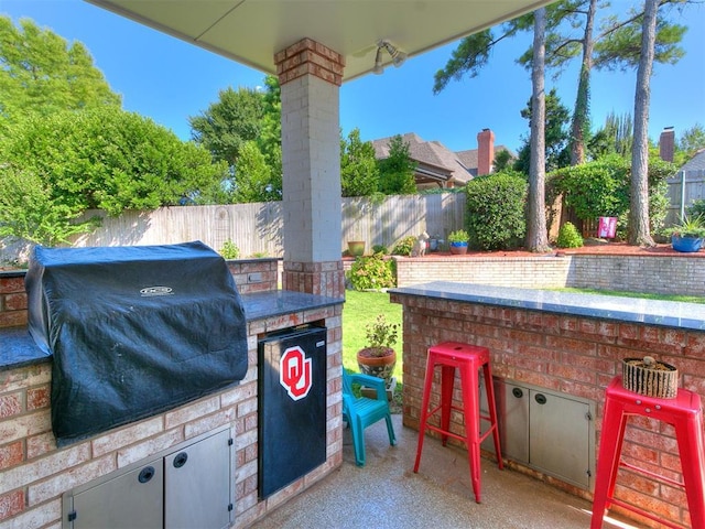 view of patio featuring exterior bar, area for grilling, and a grill