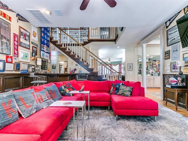 living room featuring wood-type flooring, decorative columns, and ceiling fan