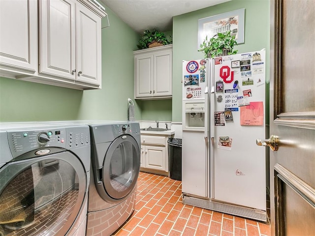 washroom with cabinets, washer and clothes dryer, and sink