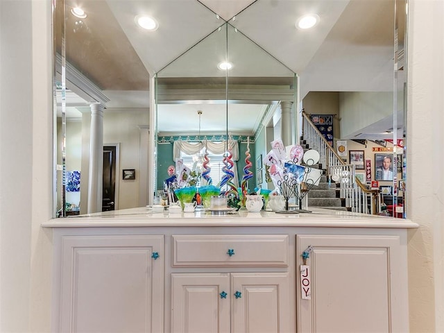 bar with white cabinets, decorative columns, and vaulted ceiling