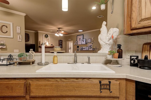 kitchen featuring backsplash, ceiling fan, ornamental molding, and sink