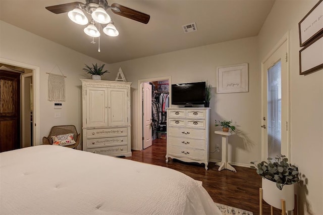 bedroom with a closet, a spacious closet, dark hardwood / wood-style flooring, and ceiling fan