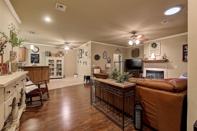 living room featuring hardwood / wood-style flooring, ceiling fan, and crown molding