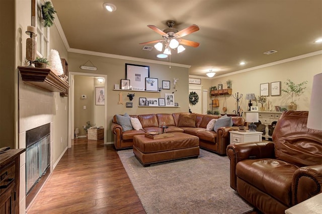 living room featuring a tiled fireplace, ceiling fan, wood-type flooring, and ornamental molding