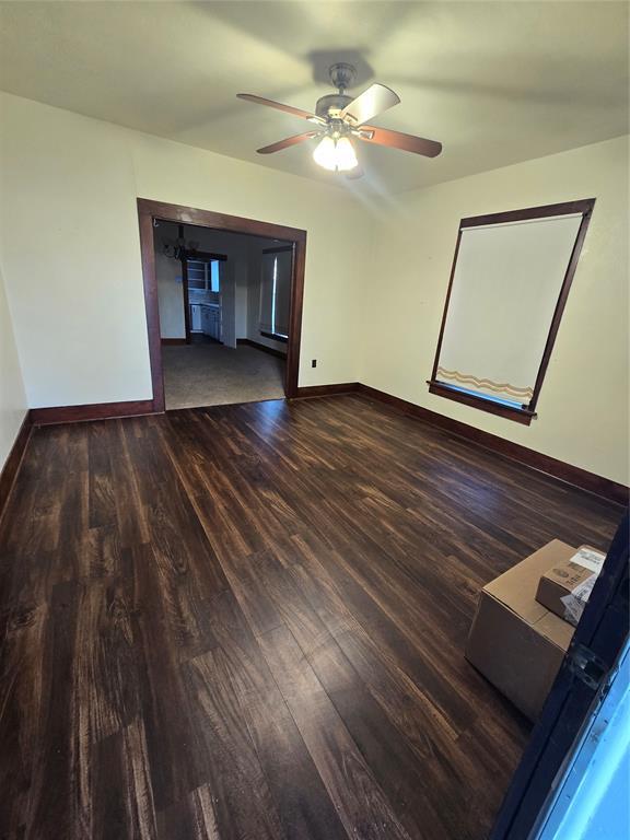 empty room with ceiling fan and dark wood-type flooring