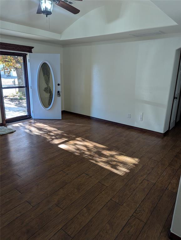 interior space featuring vaulted ceiling, a raised ceiling, dark wood finished floors, and ceiling fan