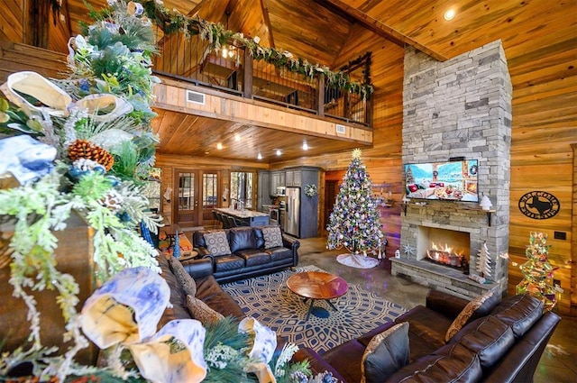 living room with high vaulted ceiling, a stone fireplace, wood ceiling, and wooden walls