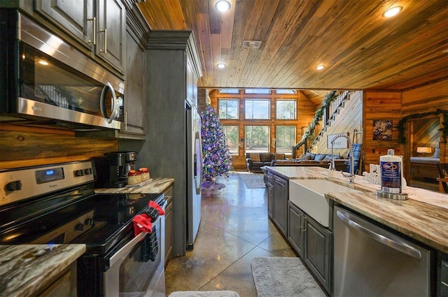 kitchen featuring sink, light stone counters, wood walls, wood ceiling, and appliances with stainless steel finishes