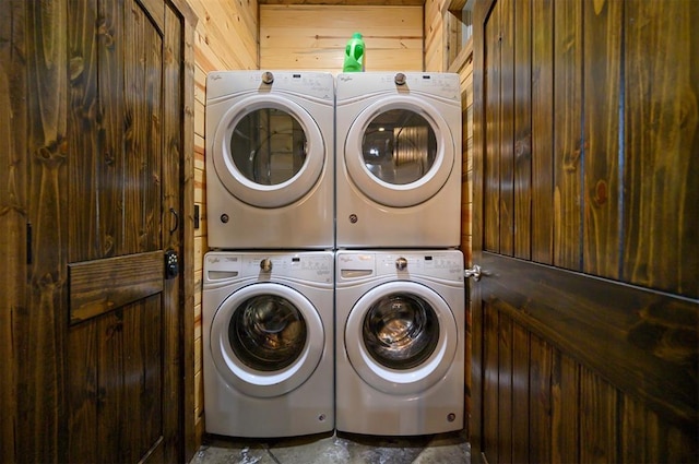 laundry area with washer and clothes dryer, stacked washing maching and dryer, and wooden walls