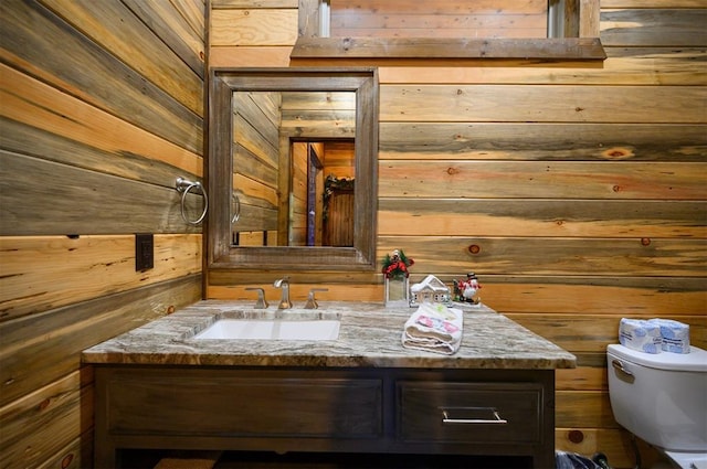 bathroom featuring vanity, toilet, and wooden walls