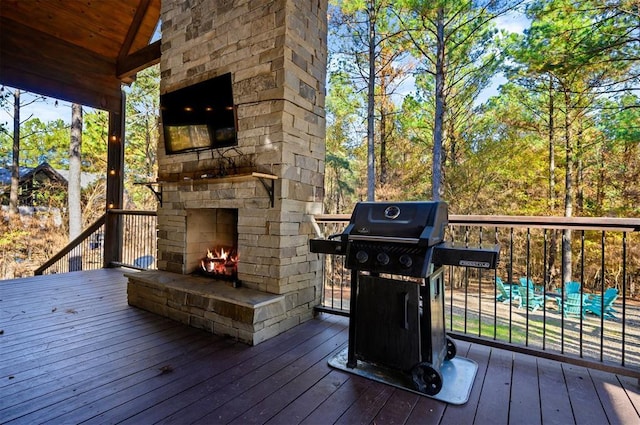 wooden deck with grilling area and an outdoor stone fireplace