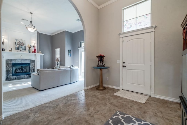 foyer entrance with a fireplace, light tile patterned floors, and ornamental molding