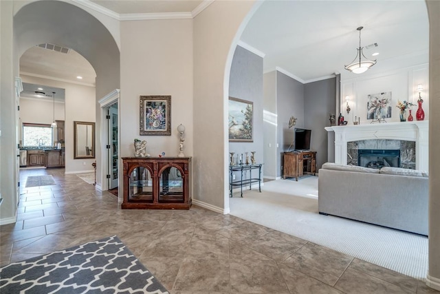 living room featuring sink, a high ceiling, a premium fireplace, carpet, and ornamental molding