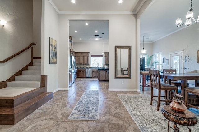 entrance foyer with a notable chandelier, ornamental molding, sink, and a towering ceiling