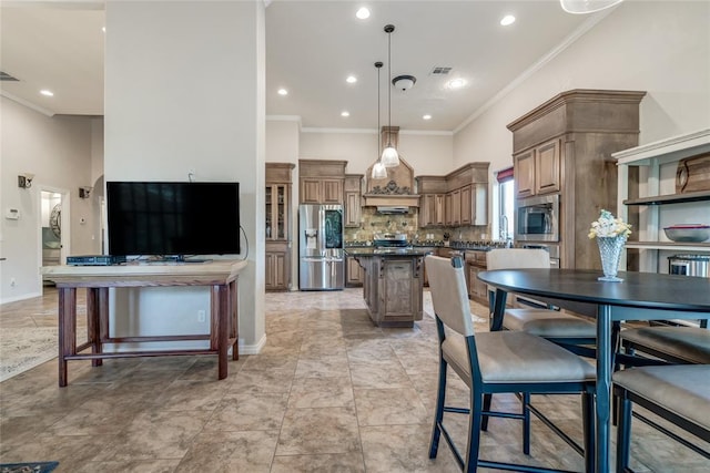 kitchen featuring backsplash, stainless steel appliances, crown molding, a kitchen island, and hanging light fixtures