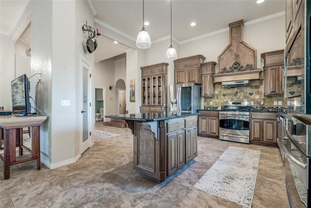 kitchen featuring hanging light fixtures, stainless steel appliances, a breakfast bar area, a kitchen island, and custom range hood