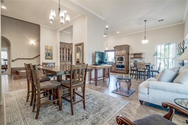 tiled dining area with a high ceiling, an inviting chandelier, and ornamental molding