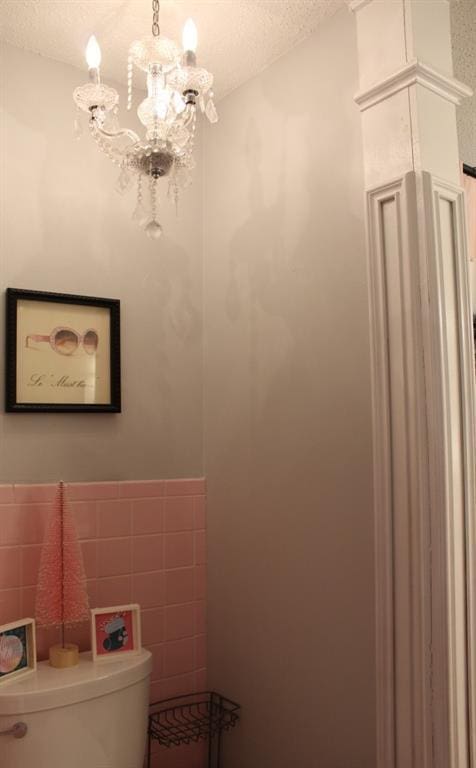 bathroom featuring a textured ceiling, toilet, tile walls, and a chandelier