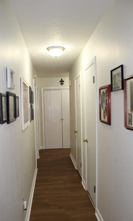 hallway with dark hardwood / wood-style flooring and a textured ceiling