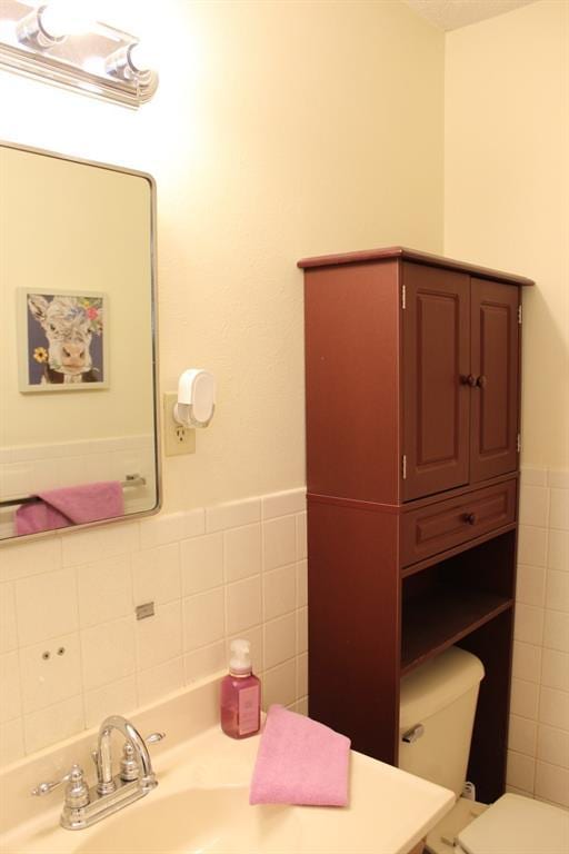 bathroom with sink, tile walls, and toilet