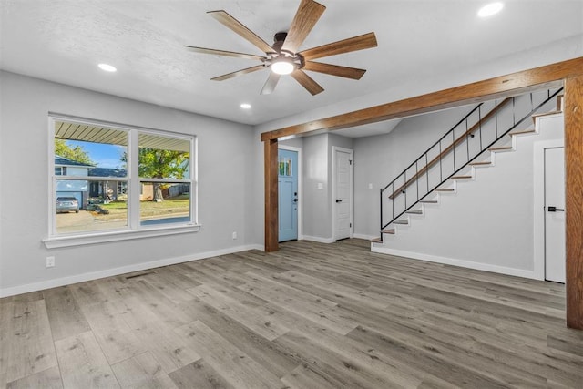 unfurnished living room featuring ceiling fan and hardwood / wood-style flooring