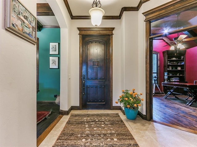 foyer entrance featuring crown molding, ceiling fan, and light tile patterned floors