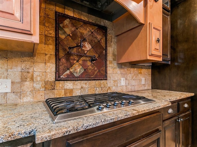 kitchen with stainless steel gas cooktop, backsplash, and light stone counters