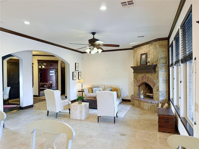 tiled living room with crown molding, ceiling fan, and a fireplace