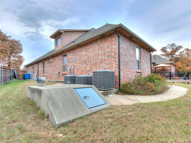 entry to storm shelter featuring a lawn and central air condition unit